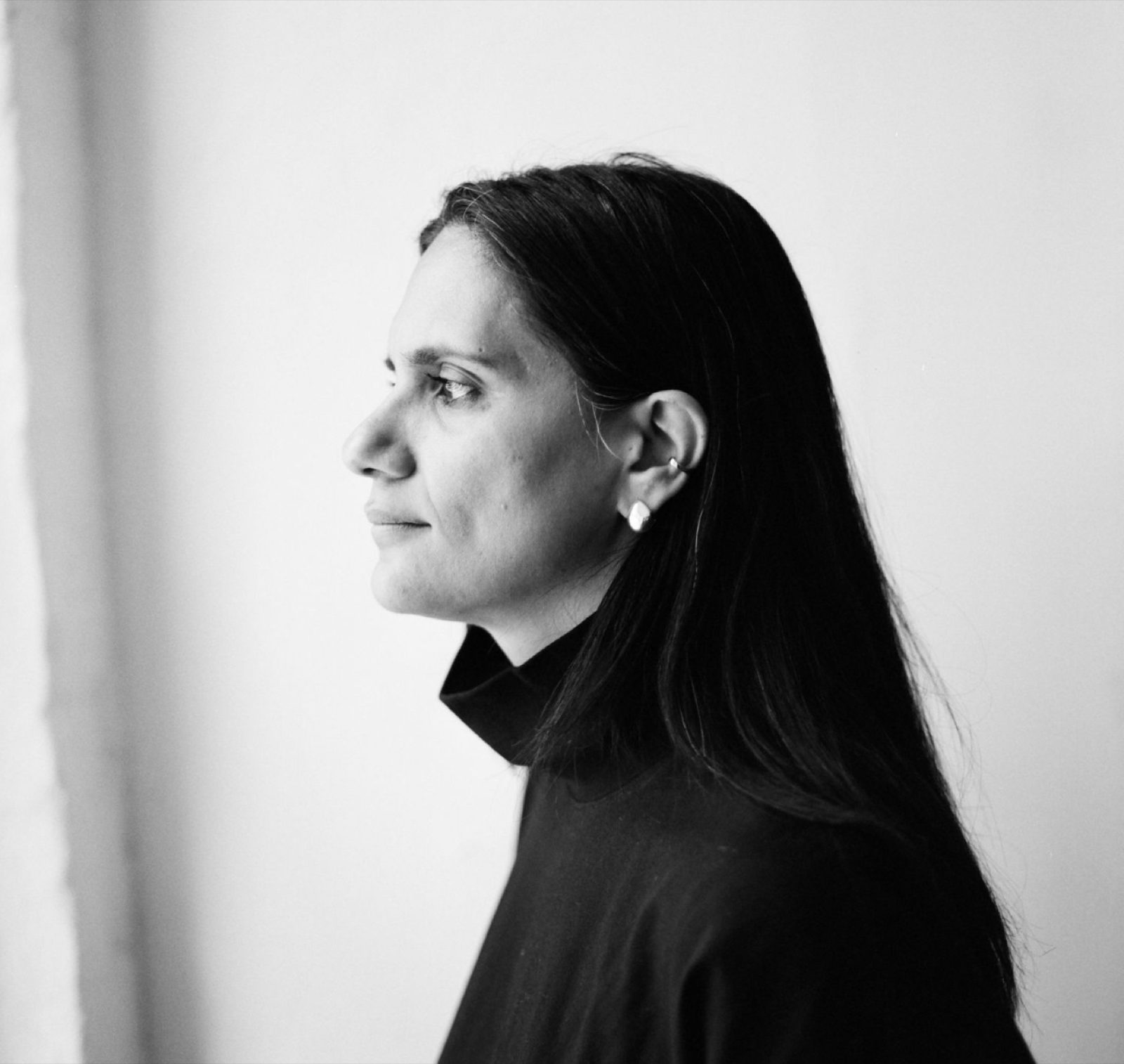 Black-and-white portrait of Francesca Sonara in profile, dark turtleneck against a white wall.