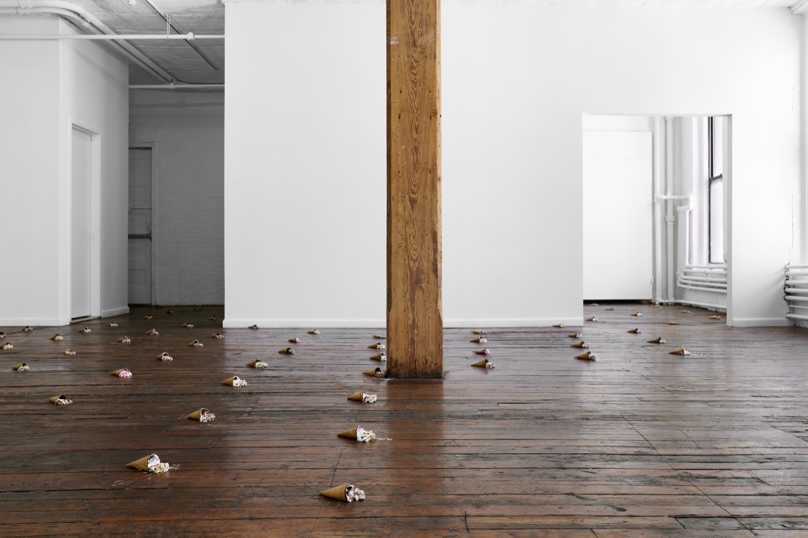 Installation view at times nonprofit arts centre — small paper cones scattered across a wood-plank floor in a white-walled SoHo loft.